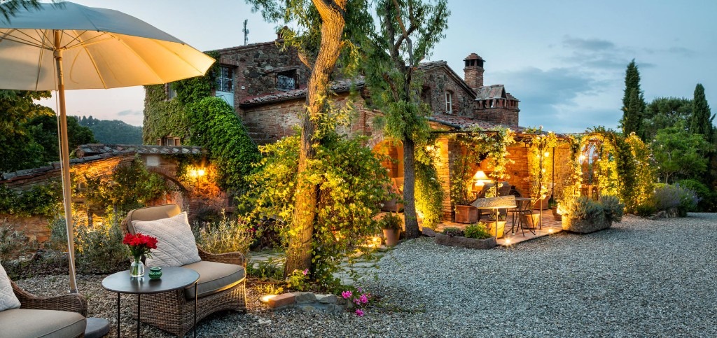 Lit stone villa terrace at dusk overlooking rolling Tuscan hills