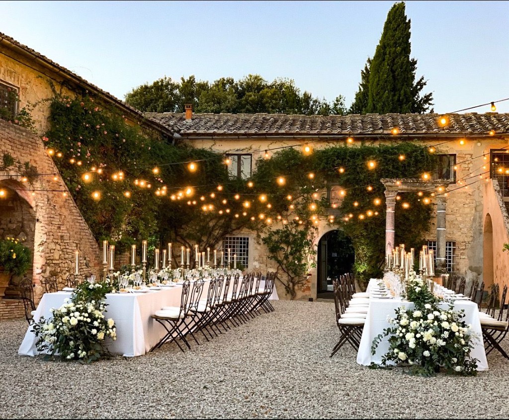 Candlelit courtyard dinner at Villa Oliveto with white florals under festoon lights
